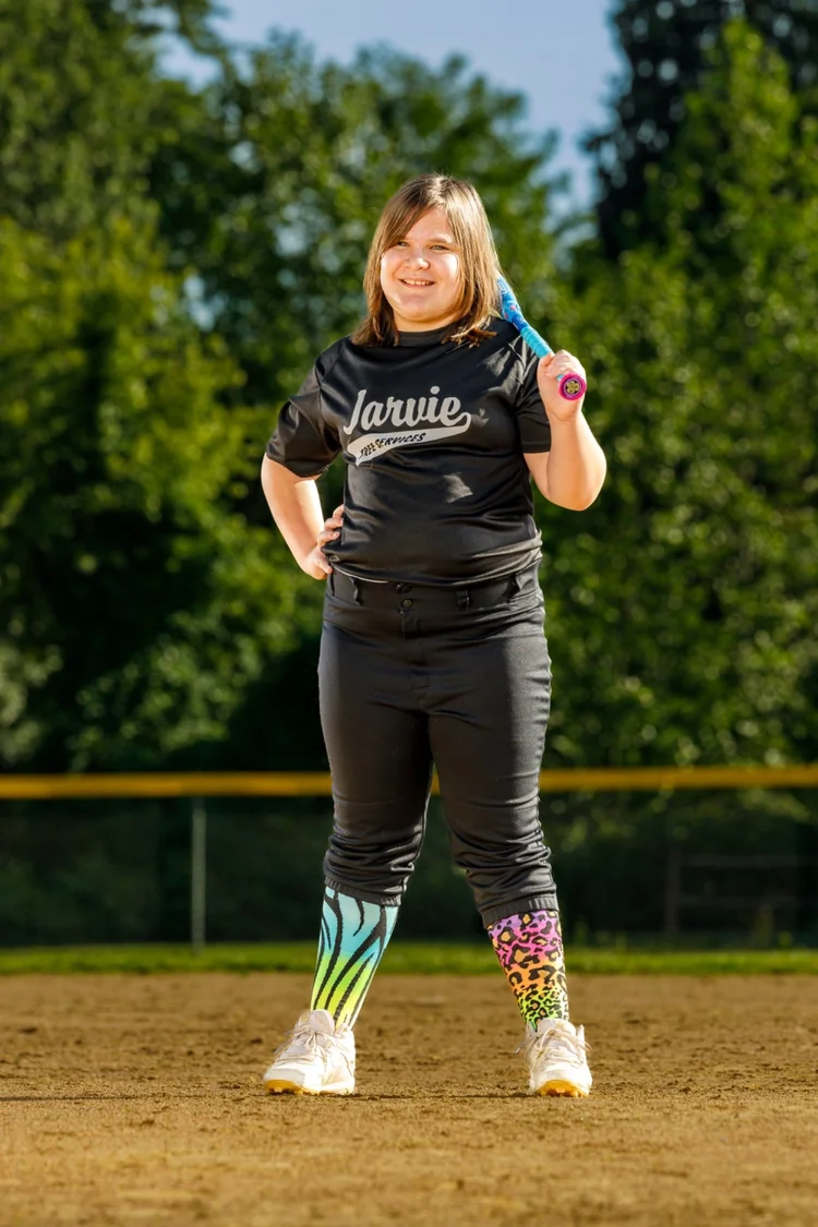 Youth softball player holding a colorful bat