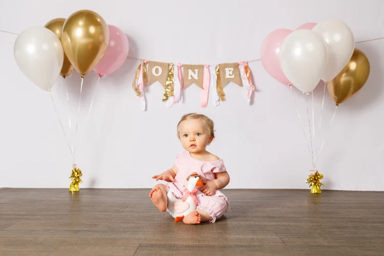 First birthday portrait with balloons and a stuffed toy