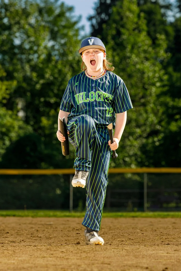 Youth baseball player posing with bats