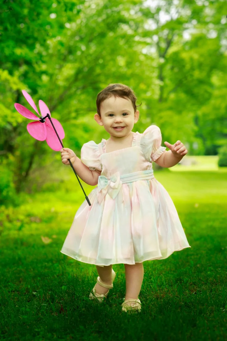 Toddler holding a pink pinwheel outdoors