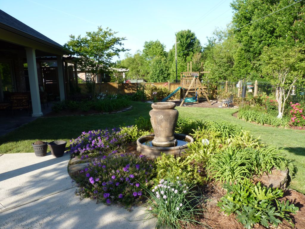 A residential backyard with a water feature and plantings