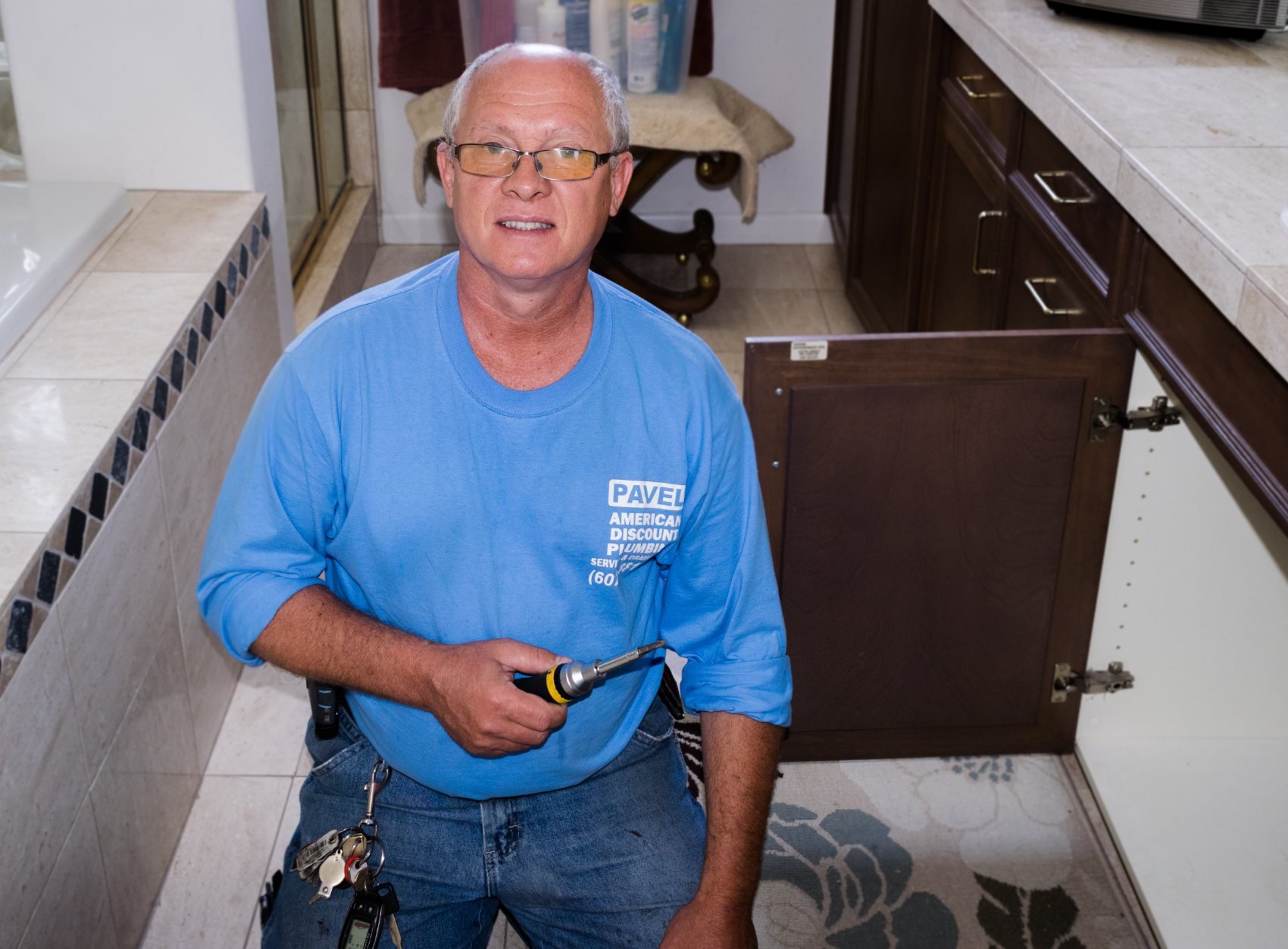 Pavel Farcas working on a cabinet plumbing repair at a Phoenix home.