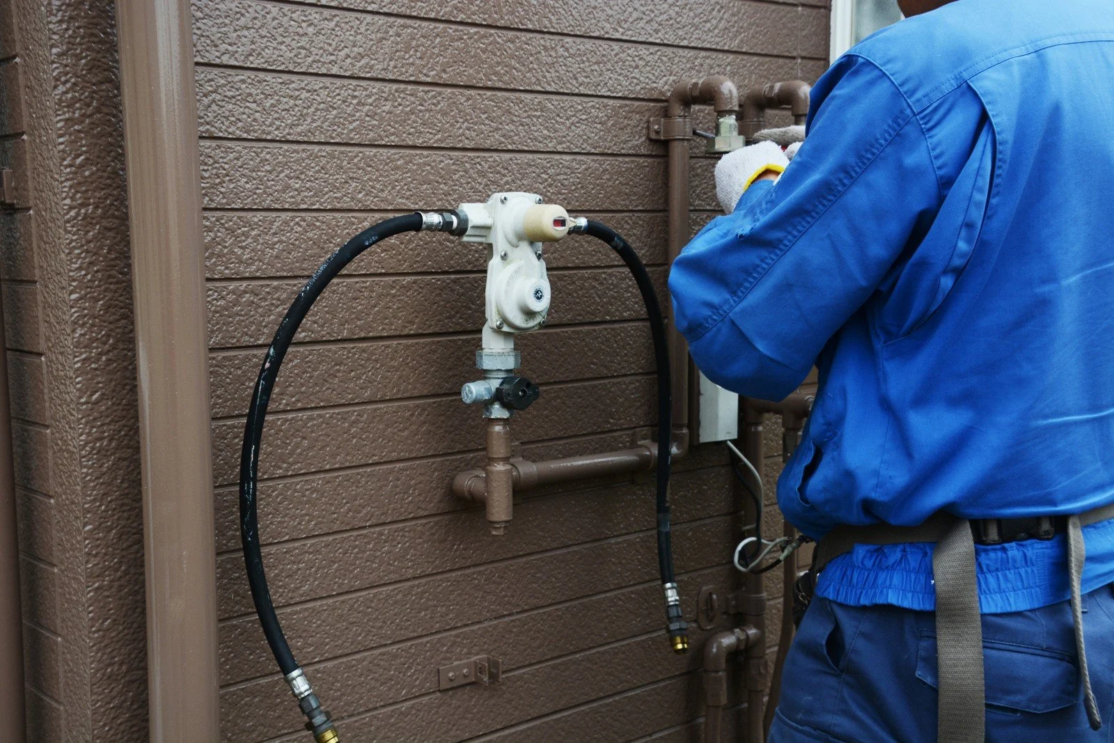 Technician working on an exterior gas meter and supply line.