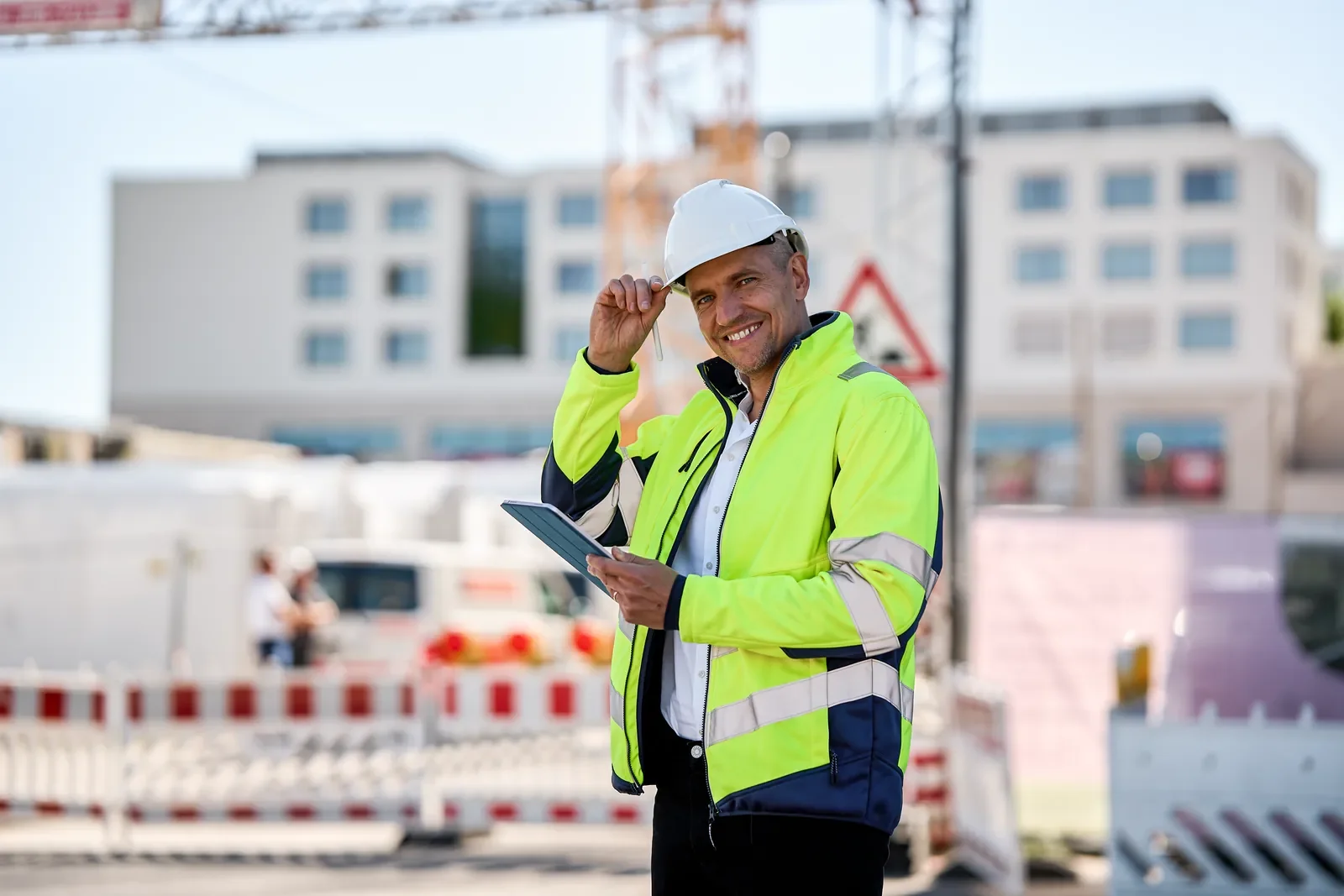 Linus Dreier mit Schutzhelm und Tablet auf einer Baustelle