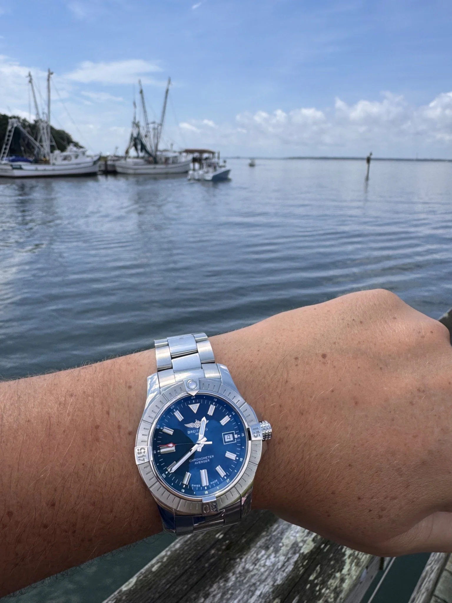 Blue dial watch photographed on the wrist beside the Charleston waterfront