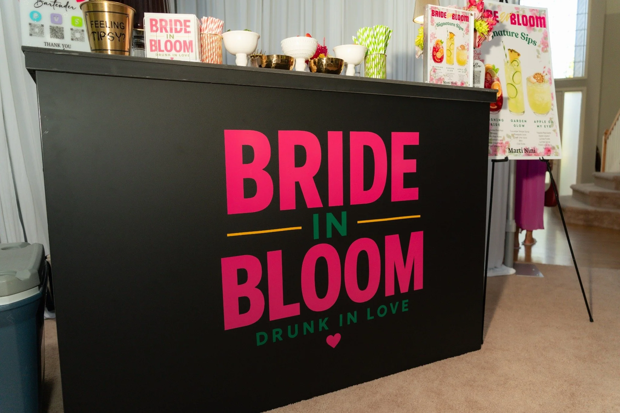 Bride in Bloom mobile bar with pink lettering, gold accents, and a signature cocktail menu