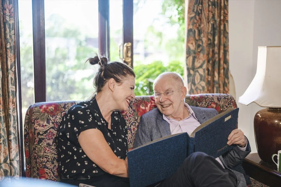 An older man and companion looking at a family photograph album