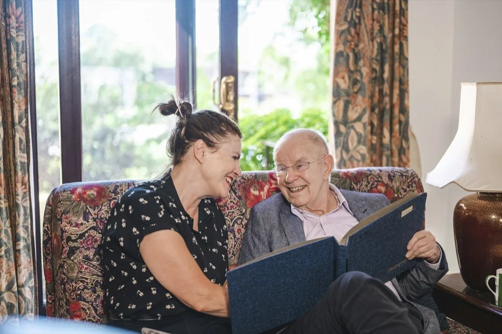An older man and companion looking at a family photograph album