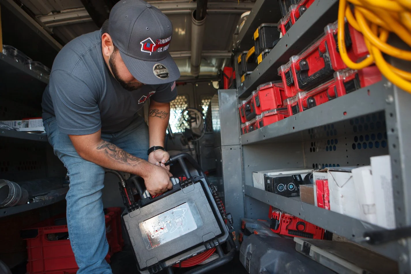 Ser Plumbing plumber lifting an equipment case from the van tool bay