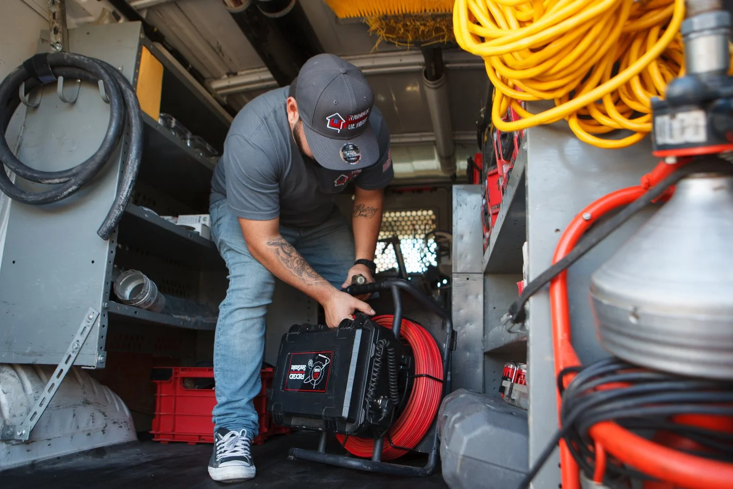 Ser Plumbing technician handling drain-cable equipment at the van