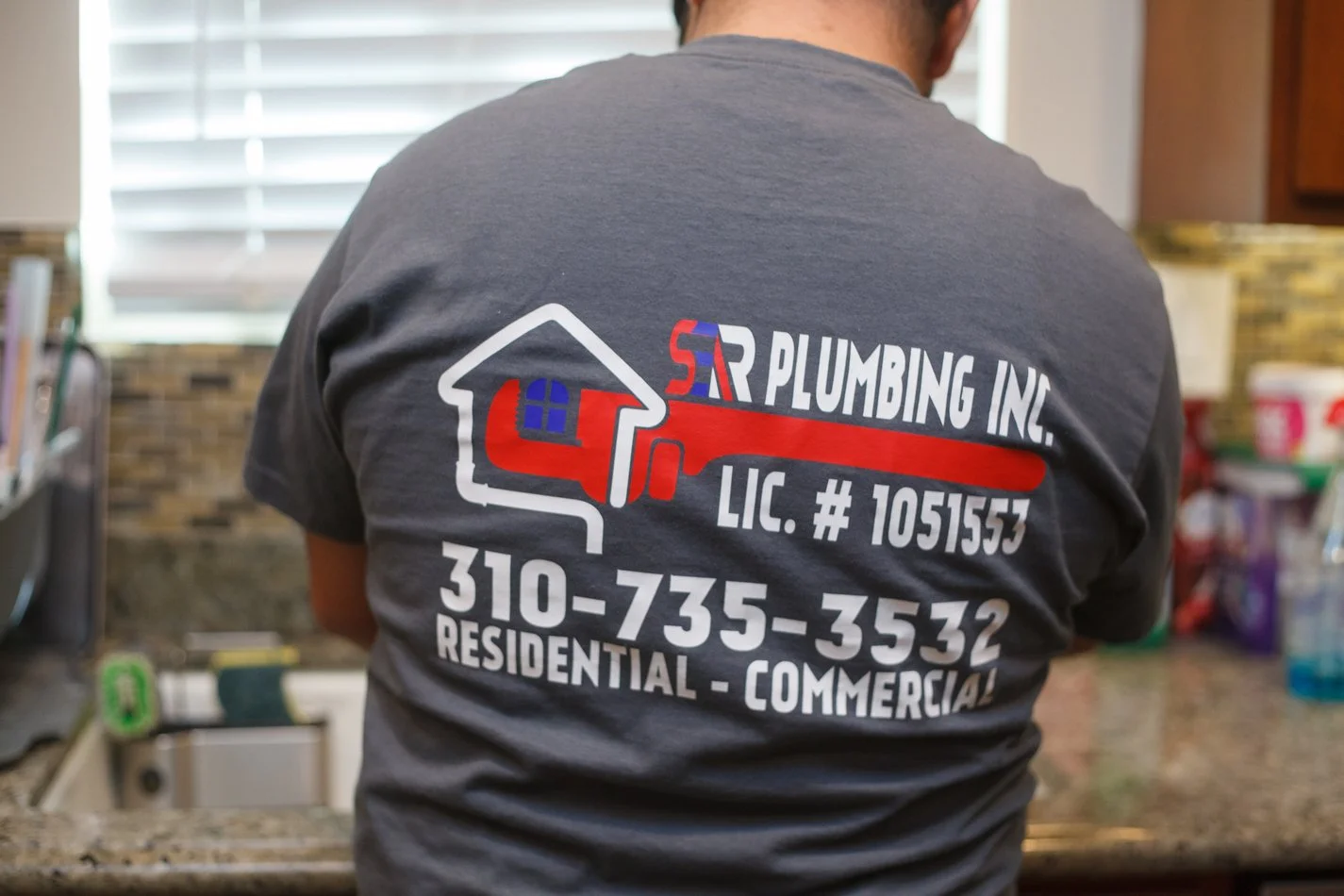 Ser Plumbing shirt showing the CSLB license number on a kitchen service call