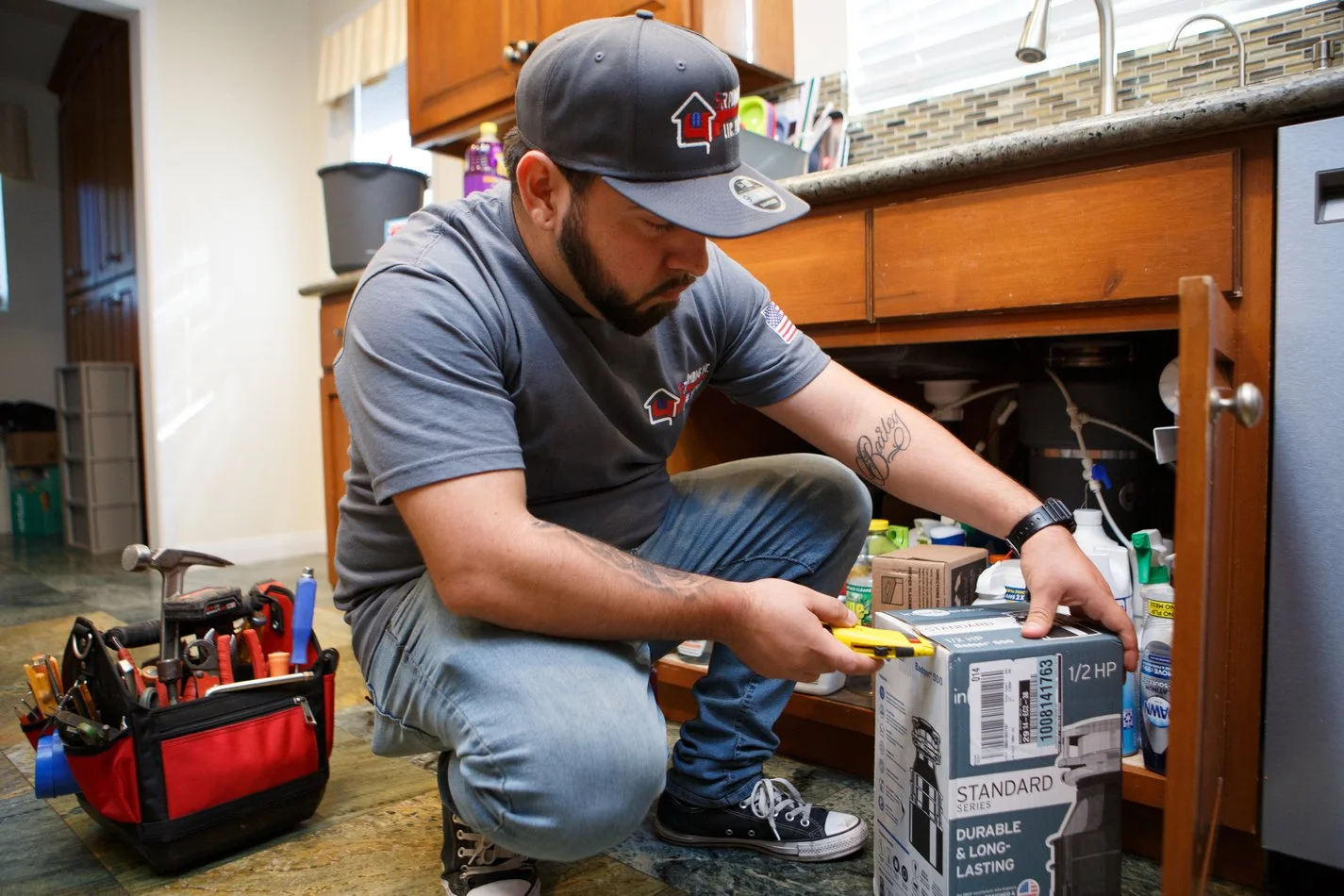 Ser Plumbing technician with a tool belt working under a sink