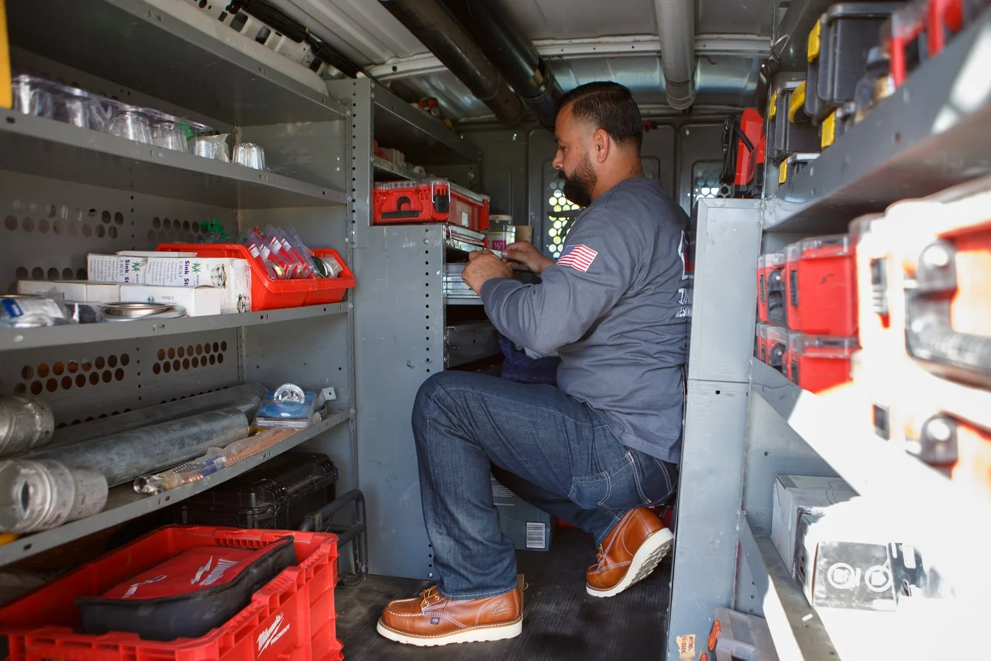 Ser Plumbing technician lifting a cased tool from the van shelving