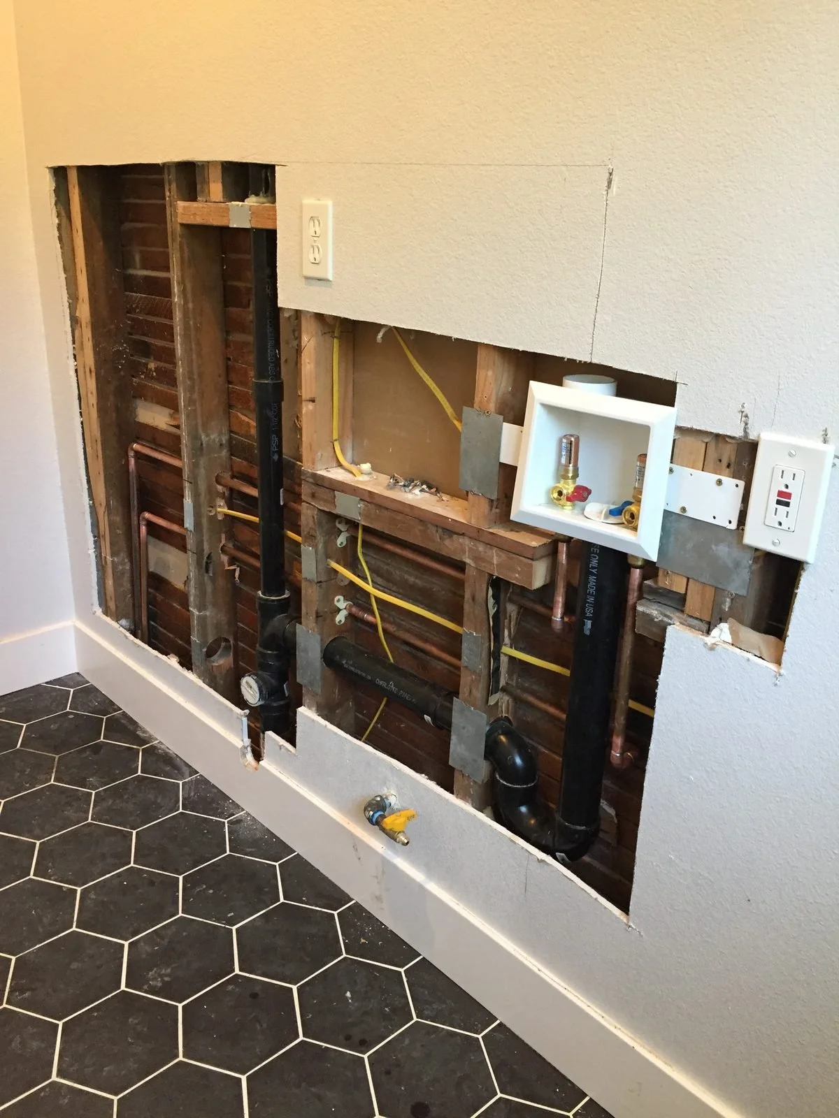 New drain and supply lines roughed in behind an opened bathroom wall — Ser Plumbing, Southeast LA County