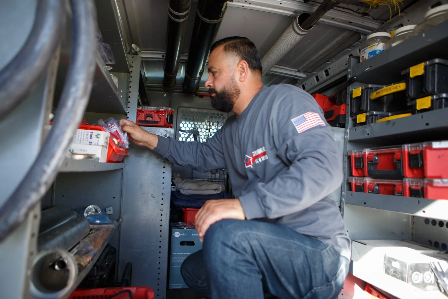 Ser Plumbing technician selecting tools from the van shelving