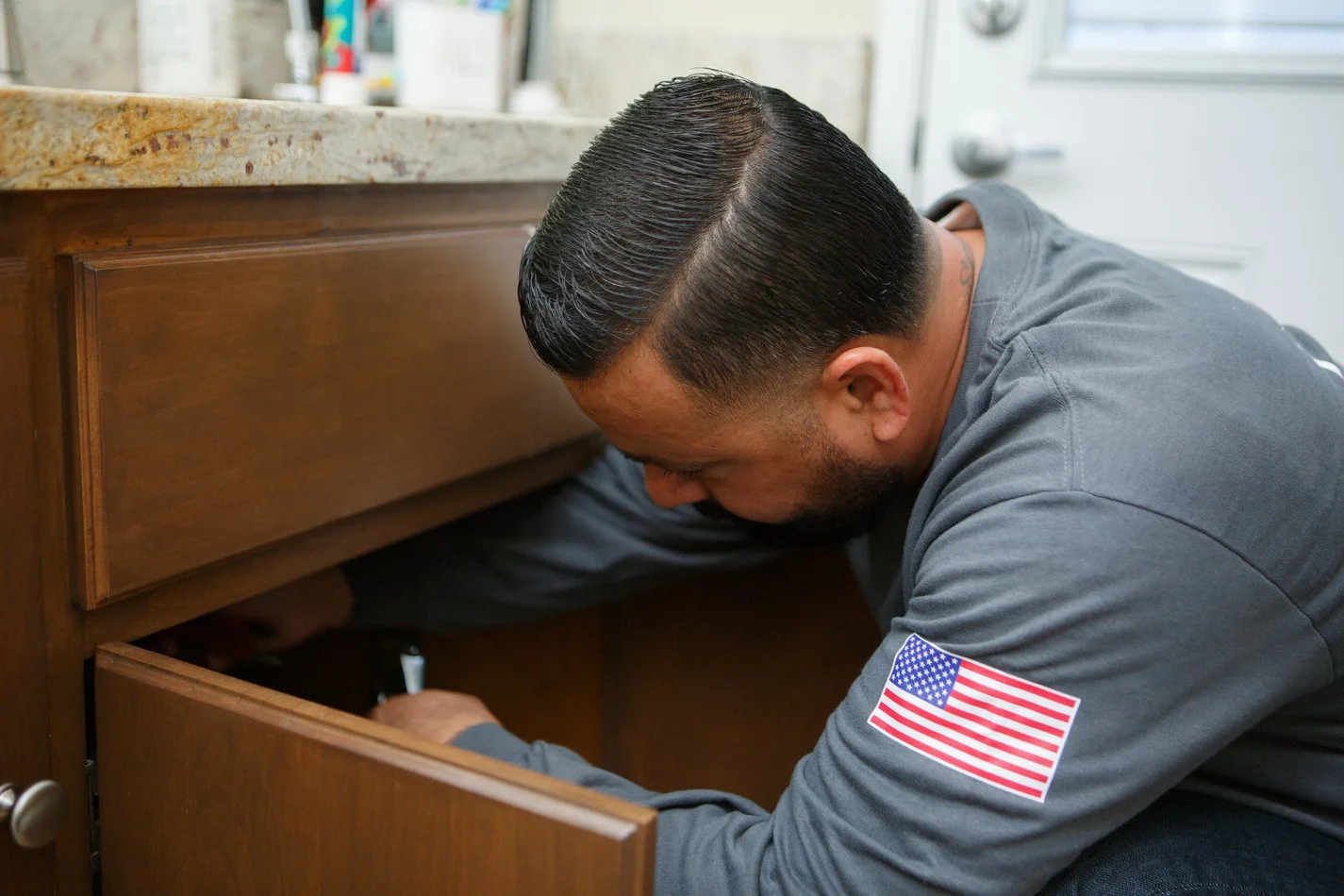 Ser Plumbing plumber inspecting a line under a Southeast LA County sink