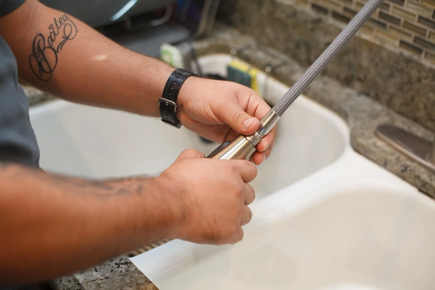 Close view of Ser Plumbing hands working on a sink supply connection