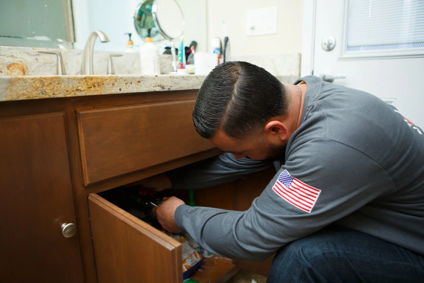 Ser Plumbing plumber reaching into an under-sink cabinet