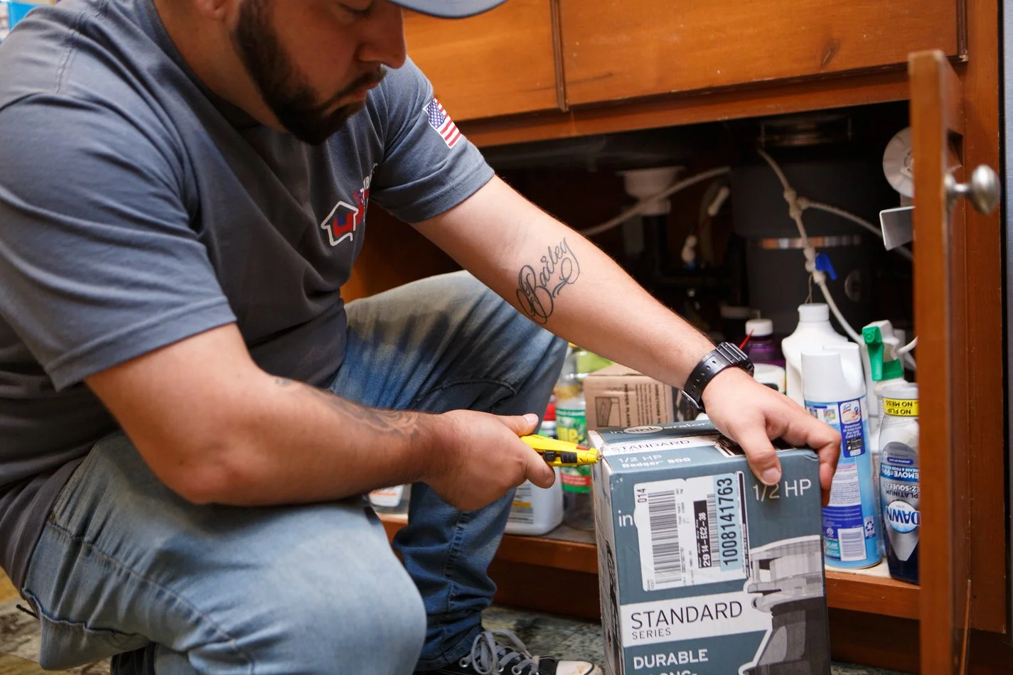 Ser Plumbing technician working inside an under-sink cabinet