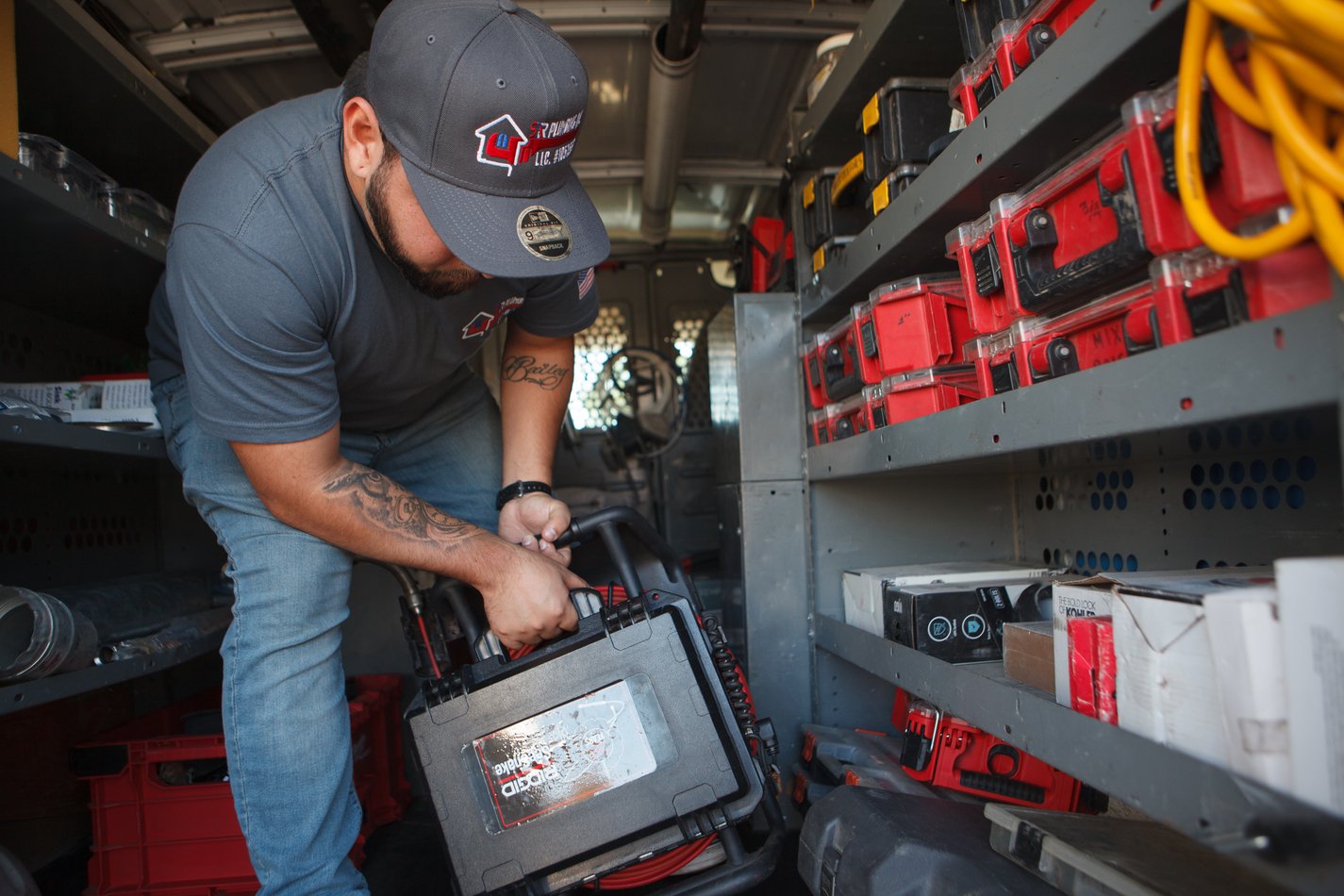 Ser Plumbing technician lifting a cased tool from the van shelving