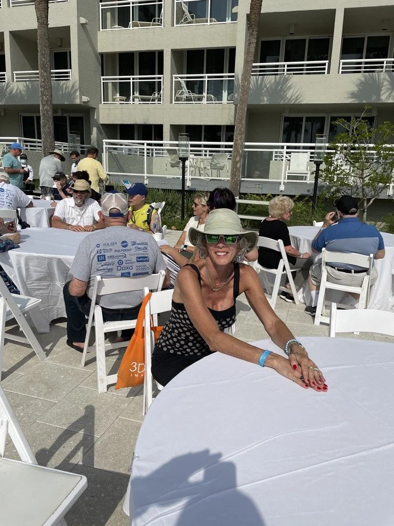 Attendees seated at outdoor tables on a resort terrace, socializing between sessions