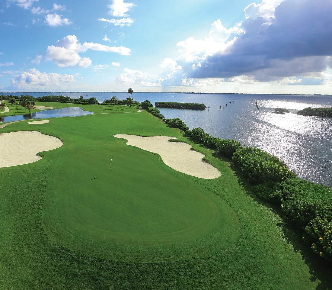 Aerial view of a championship golf green and bunkers along the water at The Resort at Longboat Key Club