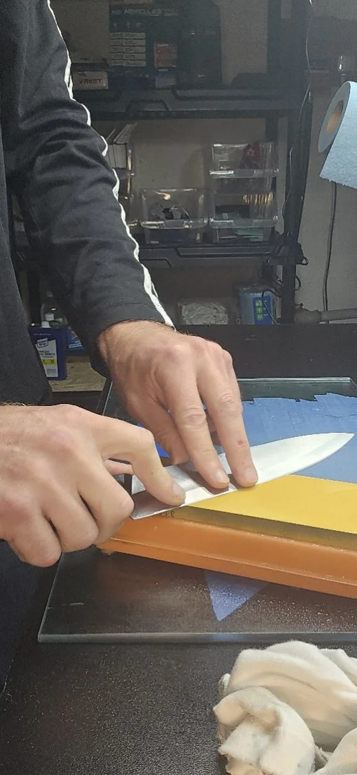 Hands guiding a kitchen knife across a sharpening stone at Apex.