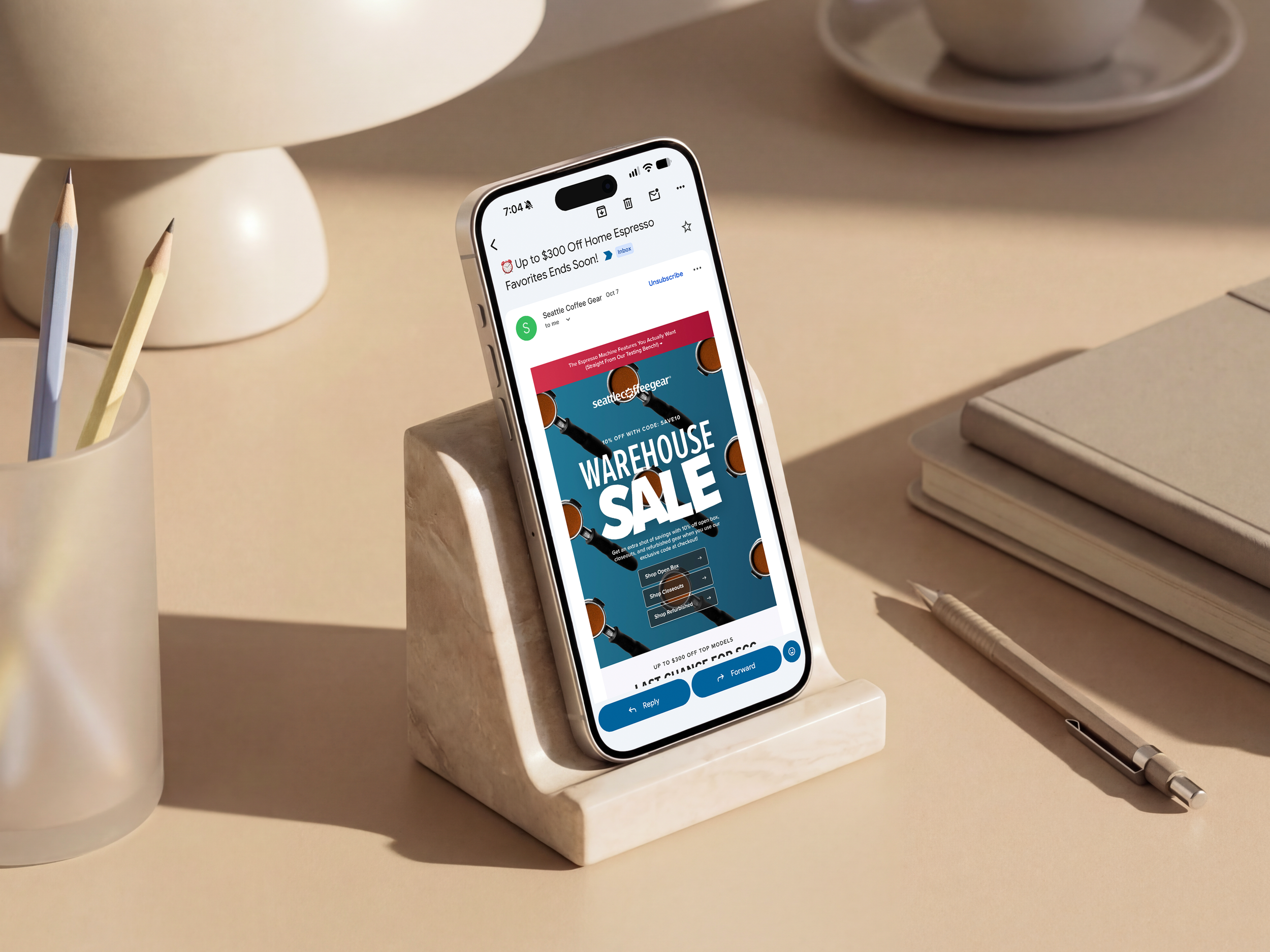 A phone on a marble stand showing a Seattle Coffee Gear Warehouse Sale email