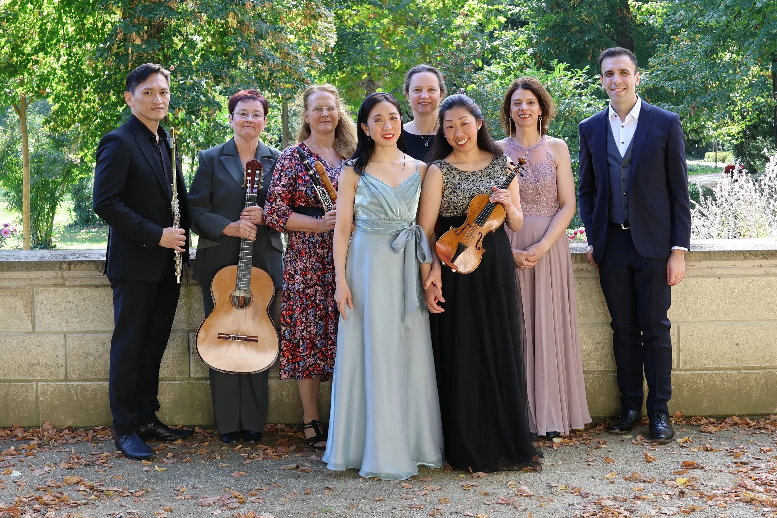 Acht Musikerinnen und Musiker mit ihren Instrumenten im Garten von Schloss Köpenick