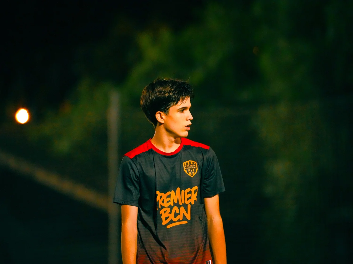 Retrato nocturno de un joven con camiseta deportiva mirando fuera de campo