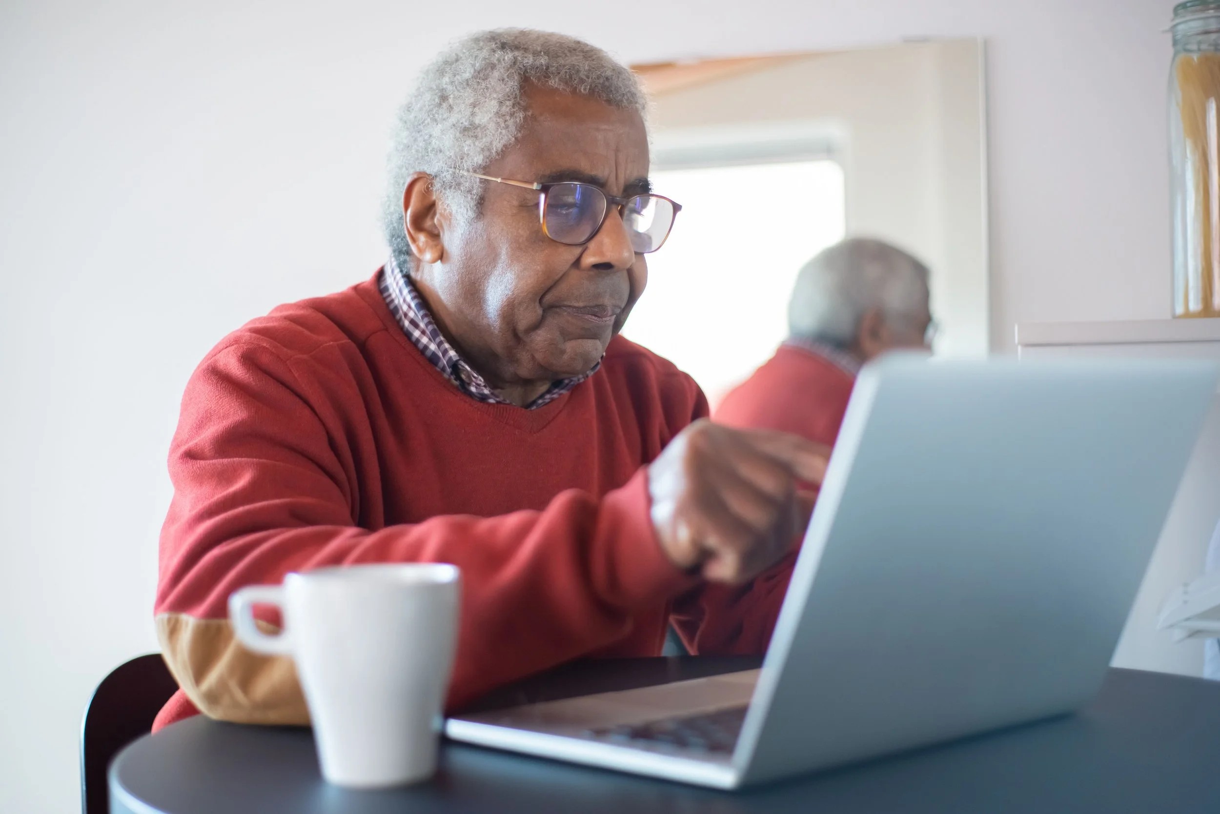 Older adult using a laptop at home.