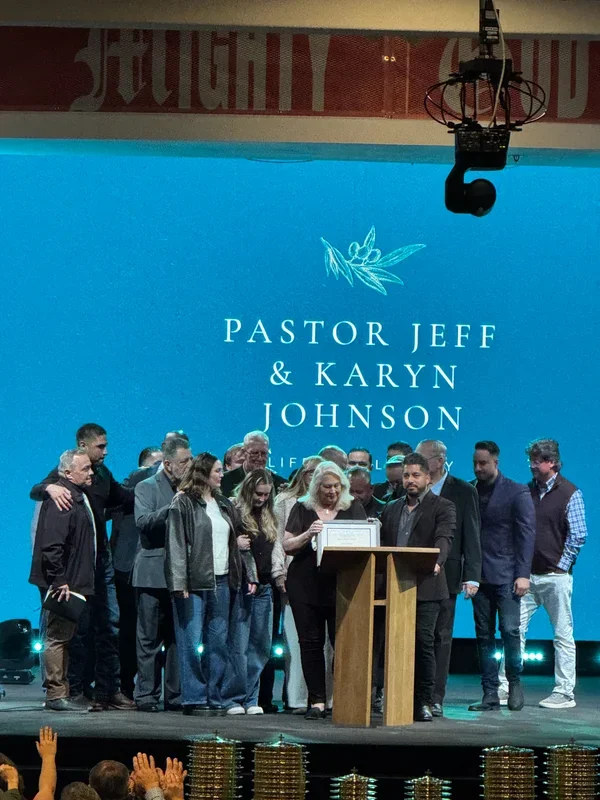 Jeff and Karyn Johnson stand with family and ministry community members during an award presentation at Calvary Chapel Downey.