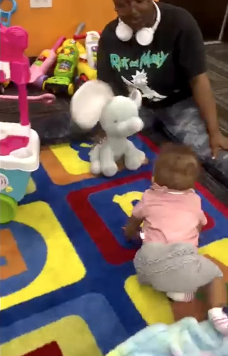 A teacher playing with an infant on a colorful rug