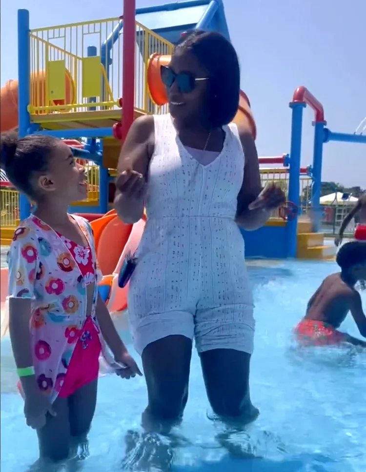 A teacher and a child laughing together at a splash pad