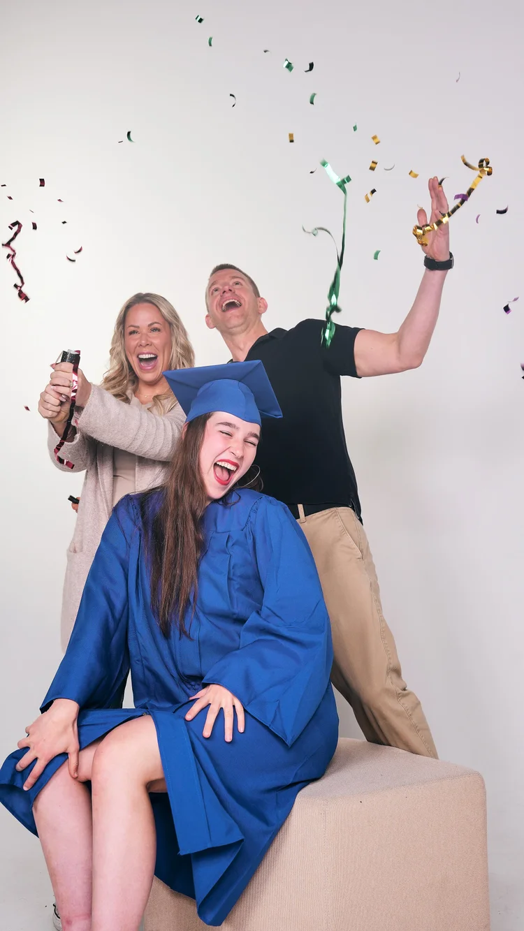 A family celebrating a graduation in the Selfography studio as confetti falls.