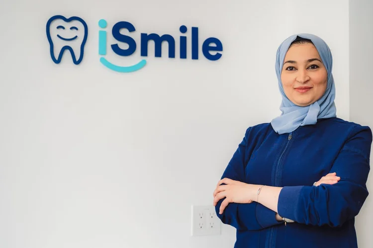 A dentist standing in front of the iSmile Dental sign.