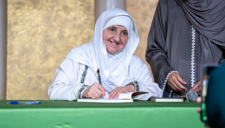 A woman signing a document at a Jannah Institute event.