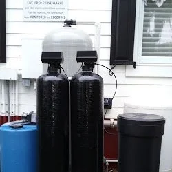 Twin black softener tanks in a garage - Pump Repair Services, Orlando FL