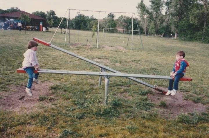 Two kids on a playground seesaw