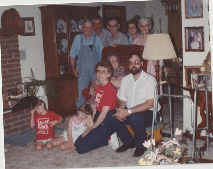 A big family gathered in a wood-paneled living room