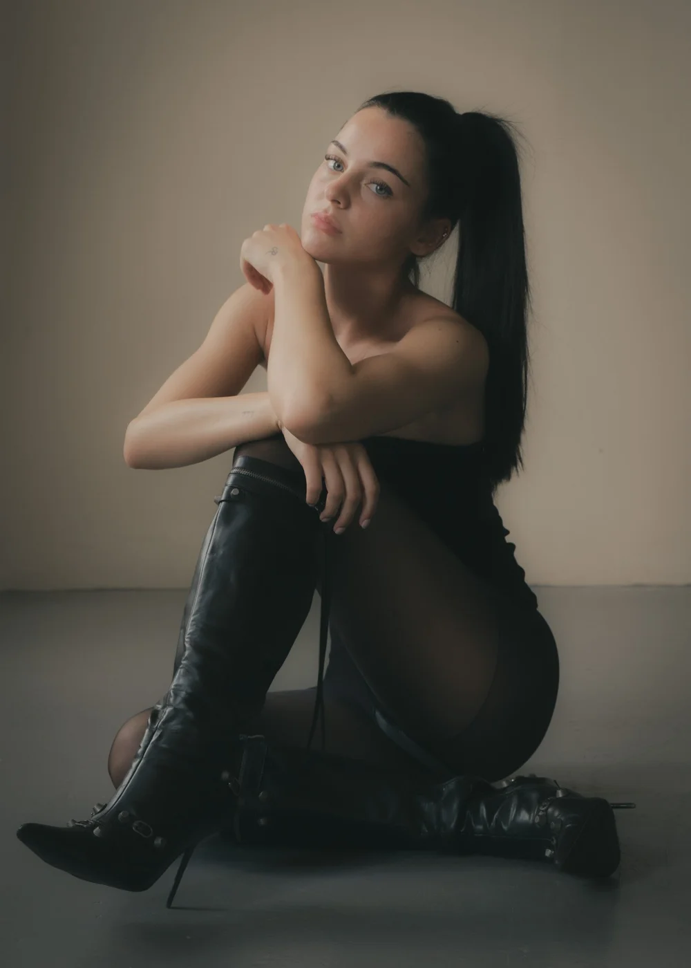 LILY × MINT — Seated fashion portrait in a black bandeau top and tall black boots, photographed by CAMR Visuals.