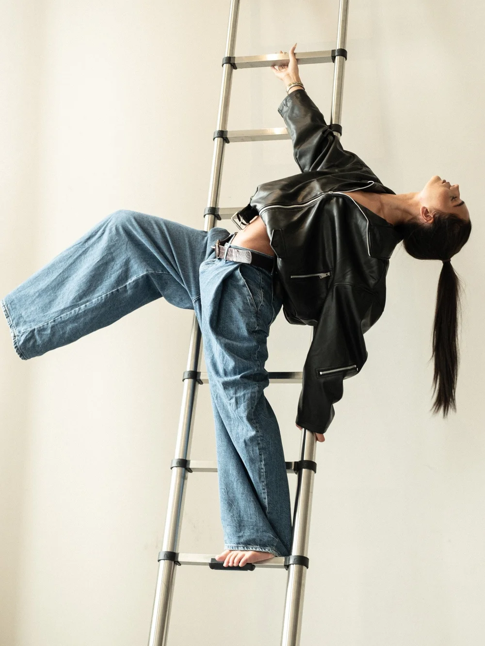 ROSIE × MINT — leather jacket and wide-leg denim, leaning back on a ladder