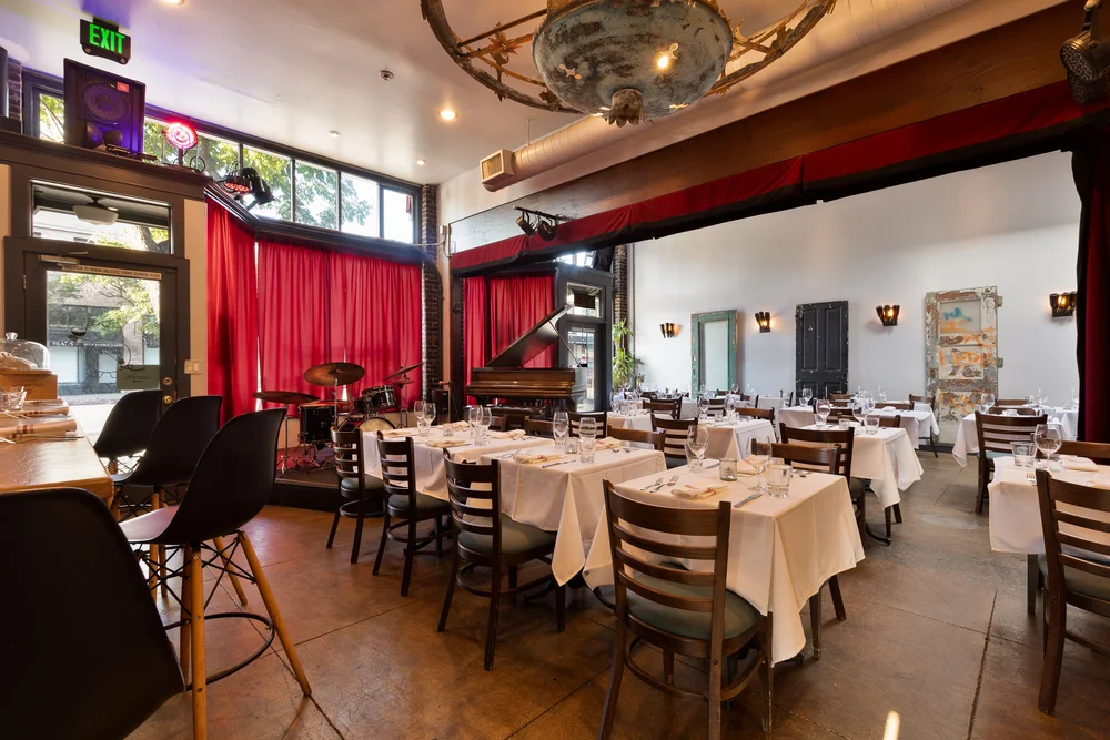 The dining room at Bacchus with red curtains and the piano