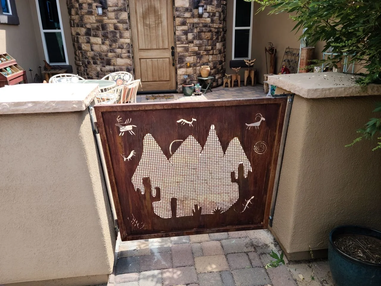 Custom desert-scene iron gate panel installed on stone facade