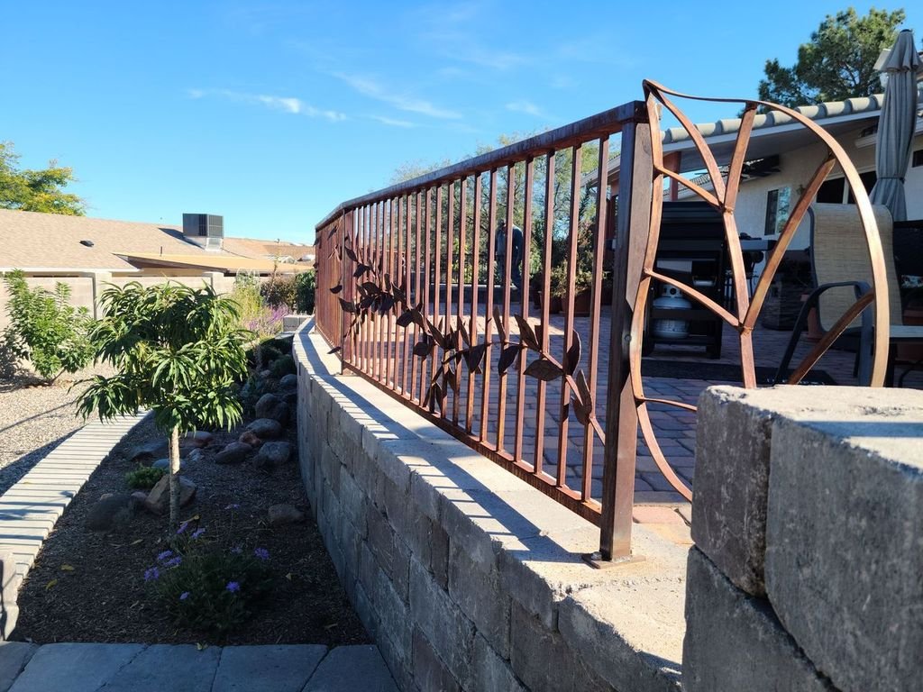 Custom leaf-motif steel railing on a stone wall, angled view