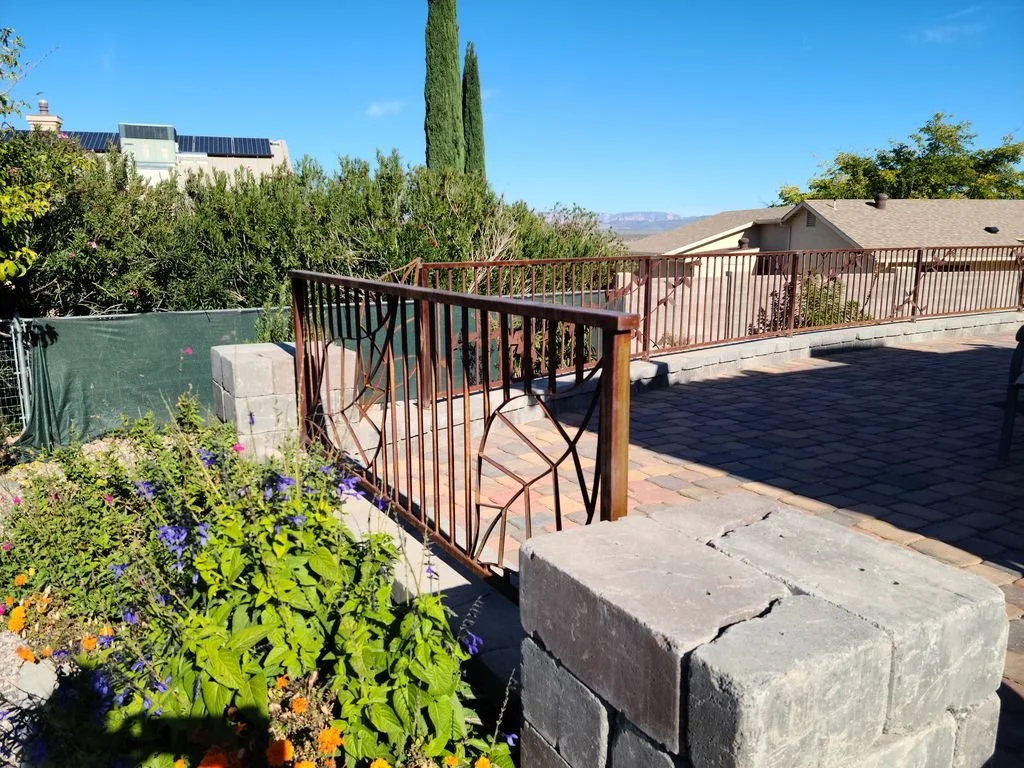Custom branch-motif steel gate set into a stone wall