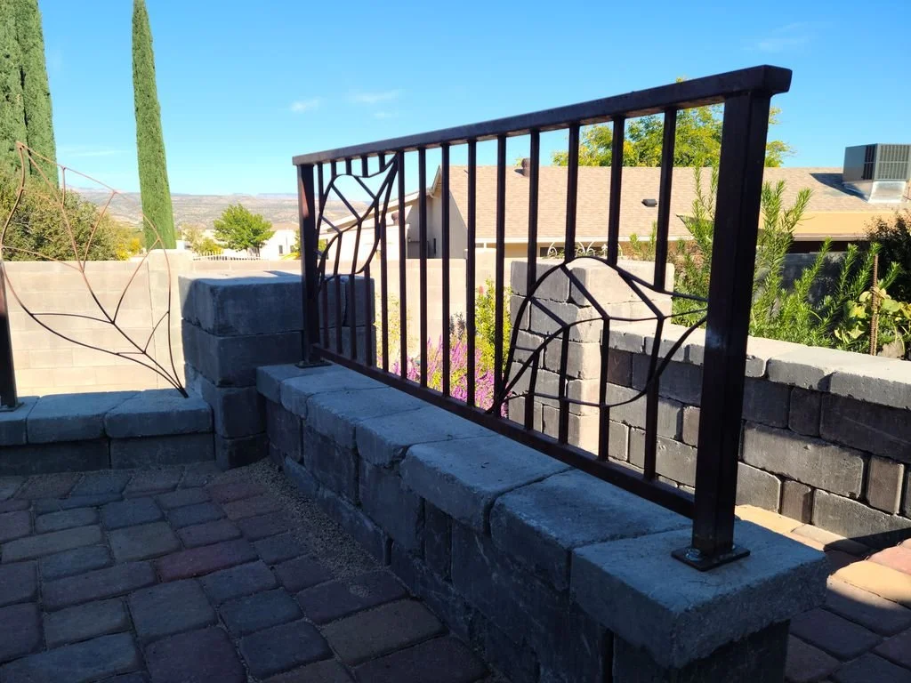 Custom leaf-motif steel railing on a block wall