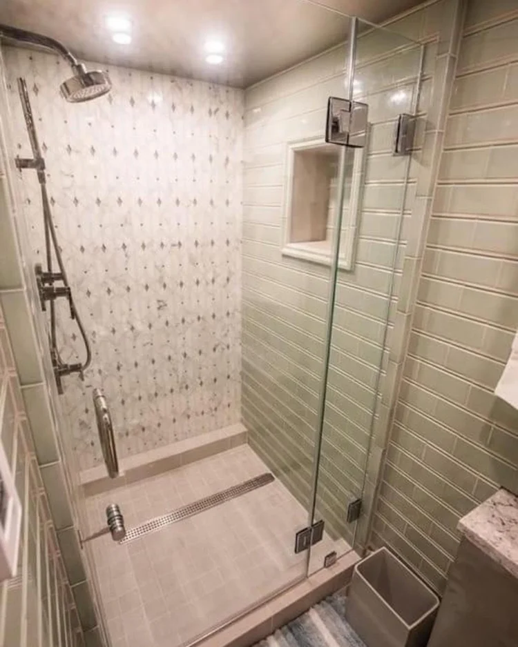 Glass shower with patterned accent tile and installed chrome fixtures.
