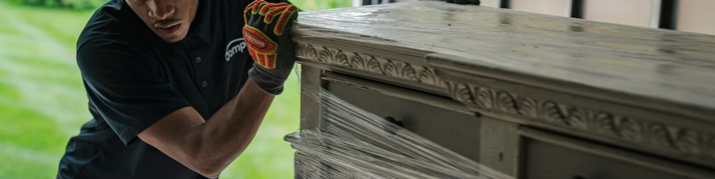 Delivery professional carefully handling a wrapped piece of wooden furniture