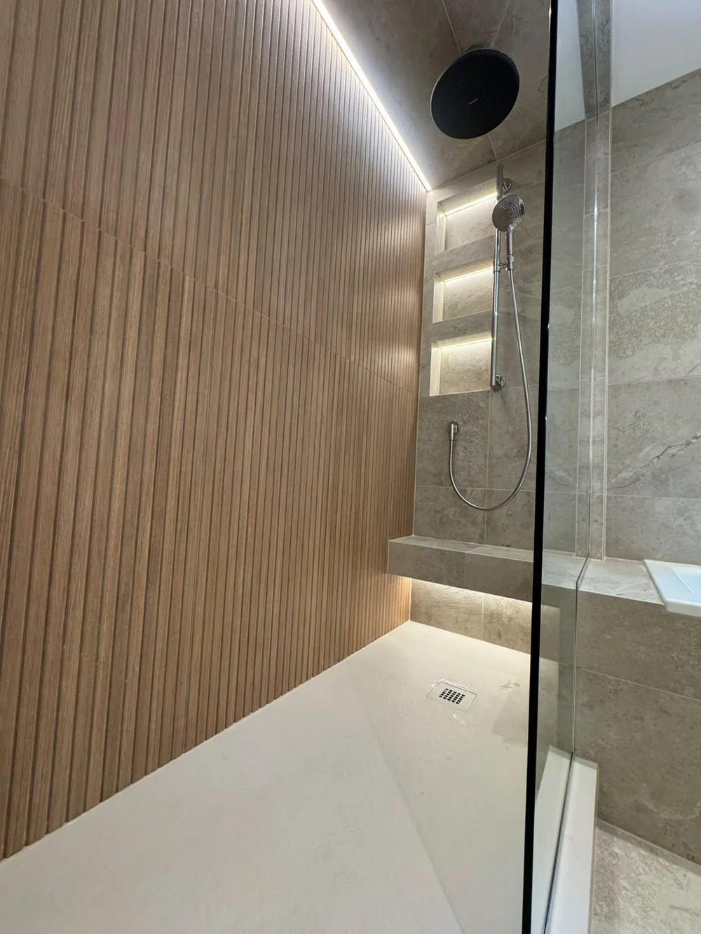 Slatted oak shower wall with tiled seat in a Bassaleg bathroom